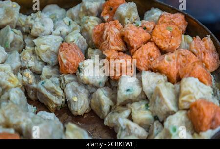 Nahaufnahme von Shumai (Shaomai) oder Kanom Jeeb' A 'Dim Sum' Chinesische traditionelle gedünstete Knödel Essen mit Garnelen und Schweinefleisch im Inneren In Metall-Tablett zum Verkauf Stockfoto