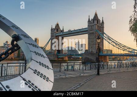 England, London, St Katherine’s Dock , Blick auf die Tower Bridge bei Sonnenuntergang mit einem Teil der Uhrmacherskulptur, der einer Sonnenuhr von Wendy ähnelt Stockfoto