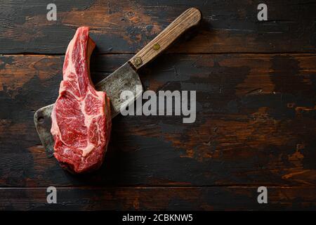 Rohes Entrecote auf Fleischspalter. Bio-Bauernhof marmorierte Prime schwarz angus Rindfleisch. Dunkler Holzhintergrund. Draufsicht. Speicherplatz kopieren. Niemand. Stockfoto