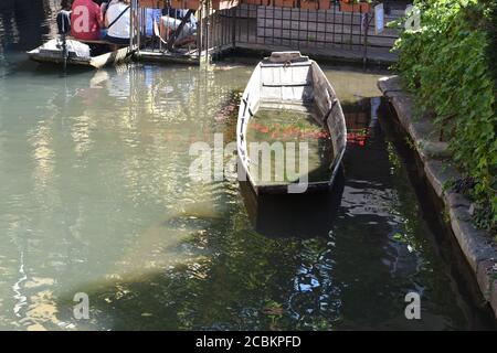 Halb versunkenes Holzboot in romantischem Kanal, kleines Venedig, ein Lauf der Lauch in Colmar, mit Fachwerkhäusern entlang der Flussufer in Frankreich. Stockfoto