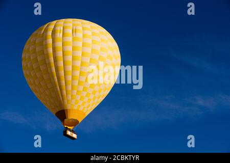 Gelber Heißluftballon schwimmt gegen blauen Himmel, Goreme Nationalpark, Kappadokien, Anatolien, Türkei Stockfoto