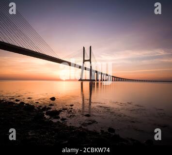 Silhouette der Vasco Da Gama Brücke gegen dramatische orange Himmel, Tejo Fluss, Lissabon, Portugal Stockfoto