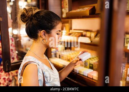 Seitenansicht einer jungen Frau, die Produkte zum Verkauf in Lissabon, Portugal, ansieht Stockfoto