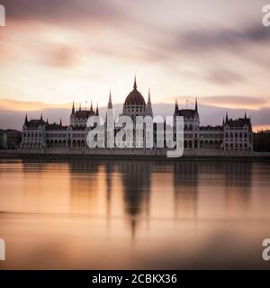 Sonnenaufgang hinter dem ungarischen Parlamentsgebäude & Donau, Budapest, Ungarn Stockfoto