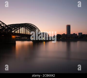 Silhouettenansicht der Hohenzollernbrücke (Hohenzollernbrücke) über den Rhein in der Abenddämmerung, Köln, Deutschland Stockfoto