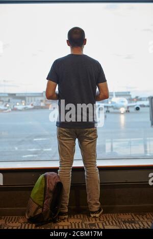 Rückansicht eines Mannes, der aus dem Fenster auf den Flughafen schaute Stockfoto