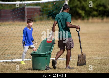 Basingstoke, Hampshire, England, Großbritannien. 2020. Platzwart mit einem Wagen Erde und Schaufel, um Löcher in den Platz während eines Jugendmatches in Basingstoke zu füllen Stockfoto