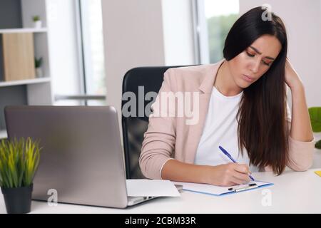 Junge weibliche Content-Managerin macht Notizen mit einem Stift Stockfoto