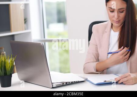 Junge weibliche Content-Managerin macht Notizen mit einem Stift Stockfoto