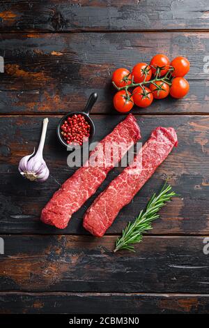 Rohes marmoriertes Rindersteak mit rosa Pfeffer und Rosmarin. Rinderschnitt genannt Denver Steak oder Bio-Top Klinge wuth Kräuter auf alten dunklen Holztisch Stockfoto