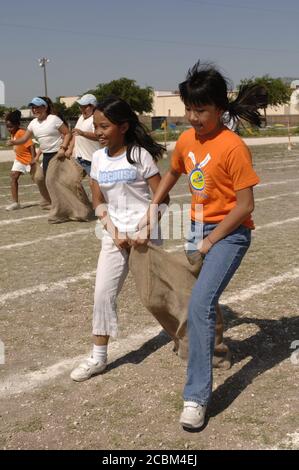 Austin Texas USA, Mai 2006: Mädchen der fünften Klasse treten beim dreibeinigen Sackrennen auf dem Schulhof während des „Leichtathletik-Tages“ an, der traditionell das Frühjahrssemester an vielen öffentlichen Grundschulen in der Region beendet. ©Bob Daemmrich Stockfoto