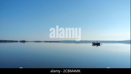 Ein kleiner verankerter Binnensee Fischtrawler am flachen ruhigen See Pohjois-Konnevesi am Sommerabend, Finnland Stockfoto