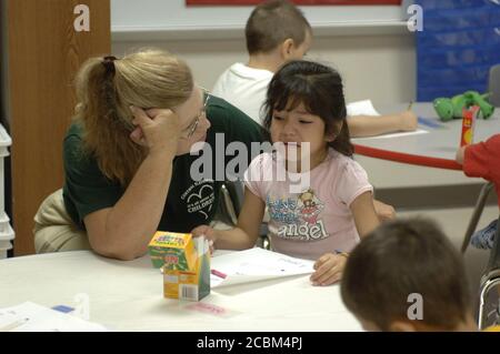 Mabank, Texas, USA, 19. August 2006: Lehrerin tröstet einen verärgerten hispanischen Kindergartner während der ersten Schulwoche an der Mabank Central Elementary School. Stockfoto