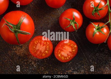 Frische Kirschtomaten auf einem Metall rustikalen alten Hintergrund halb geschnitten und ganze Kunst. Stockfoto
