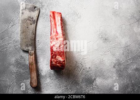 Roh schwarz angus Entrecote oder Scotch Filetcut mit dem Fleisch american Cleaver Messer über grauen Stein Tisch Schiefer Schneiden Draufsicht. Leerzeichen für Text Stockfoto