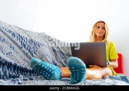 Lächelnde Geschäftsfrau, die zu Hause auf der Couch arbeitet Stockfoto