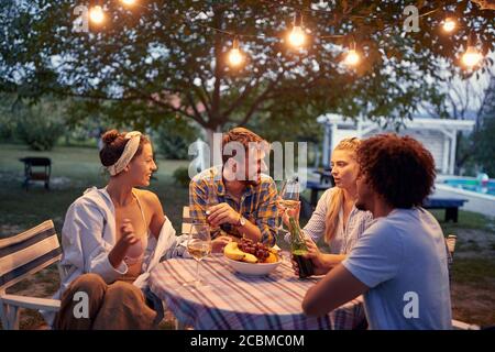 Junge glückliche Menschen genießen bei der Dinner-Party und Weingläser toasten. Stockfoto