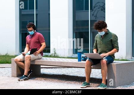 Zwei Studenten lernen, während soziale Distanz auf dem Campus zu halten. Technologie und Coronavirus-Konzept. Stockfoto