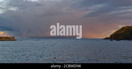 Ein Wintersturm außerhalb von Stonehaven beherbergt Breakwater und Headland und fängt das Licht der untergehenden Sonne ein, während sie hereinfegt. Stockfoto