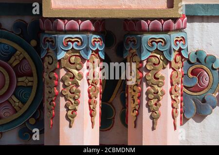 Orangene, tibetisch-buddhistische Säulen und Chackra-Rad im Hintergrund. Stockfoto