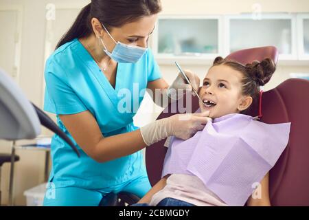 Kleines Mädchen bei einem pädiatrischen Zahnarzt mit Maske und Handschuhe Service Kinderzahnpflege in einer Zahnklinik. Stockfoto