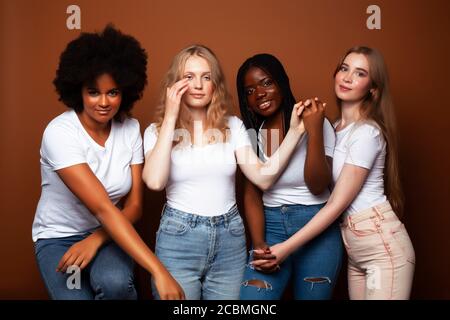 Junge hübsche kaukasische, afro, skandinavische Frau posiert fröhlich zusammen auf braunem Hintergrund, Lifestyle diverse Nationalität Menschen Konzept Stockfoto