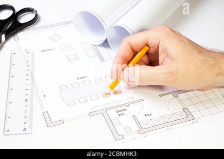 Nahaufnahme eines Architekten, der mit Bleistift, Lineal und Schere an einer Blaupause arbeitet Stockfoto