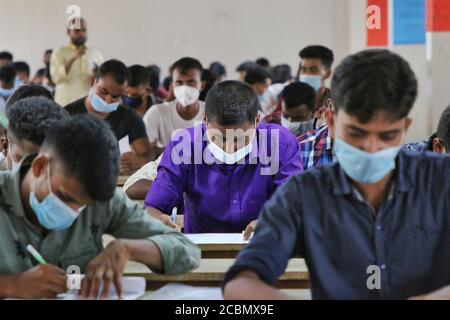 Bewerber tragen Gesichtsmasken als vorbeugende Maßnahme während der Teilnahme an einem Rekrutierungstest für Feuerwehranstellung unter der Feuerwehr und Zivilschutz Abteilung an einer Hochschule inmitten Coronavirus (COVID-19) Krise in Dhaka. Stockfoto