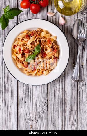 Traditionelle italienische Pasta Bolognese auf einem weißen Teller auf einem hölzernen Hintergrund, Draufsicht. Stockfoto