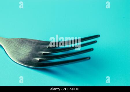 Nahaufnahme der Metallgabel auf blauem Hintergrund. Konzept des Essens Stockfoto