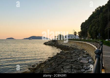 Die Strandpromenade mit einem felsigen Strand und die Inseln Tino und Palmaria am Meereshorizont bei Sonnenuntergang, San Terenzo, La Spezia, Ligurien, Italien Stockfoto