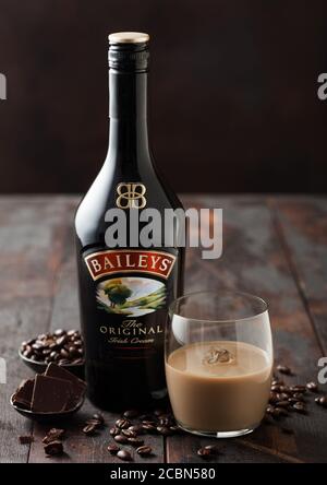 LONDON, UK - 02. JUNI 2020: Flasche und Glas Baileys Original Irish Cream auf Holzhintergrund mit Kaffeebohnen und dunkler Schokolade. Stockfoto