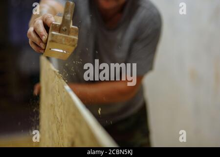 Mann, der das Holz mahlen. Mann, der mit Holz arbeitet. Hausreparatur. Textur Stockfoto