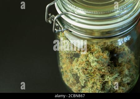 Medizinische Cannabisknospen im Glasgefäß. Platz auf schwarzem Hintergrund kopieren. Marihuana Sativa Blume Stockfoto