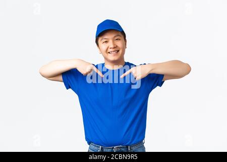 Freundlich aussehende lächelnd und zuversichtlich asiatische Lieferung Kerl in blau Uniform zeigt auf sich selbst. Kurier fördern seine Firma Service, garantieren schnell und Stockfoto