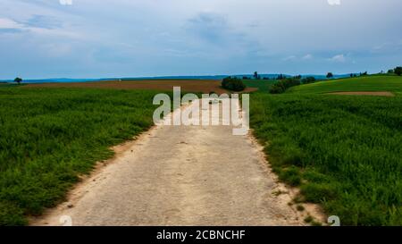 Schöne Straße umgeben von Gras bedeckten Wiesen und Bauernhöfen unter dem Blauer Himmel Stockfoto
