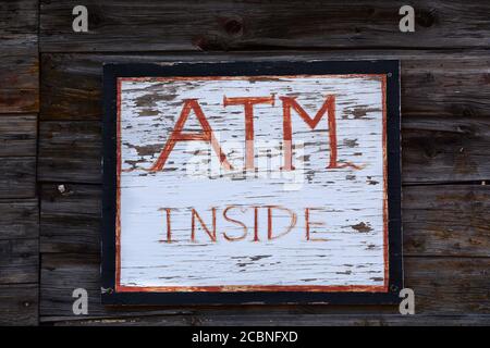 Ein handgefertigtes Schild weist Kunden darauf hin, dass sich im Laden ein Geldautomat befindet. Stockfoto