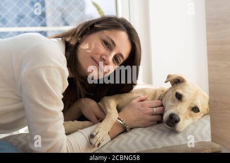 Porträt einer jungen Frau mit Hund. Mädchen drinnen zu Hause mit ihrem Hund. Stockfoto