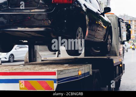 Black Broken Car auf einem Abschleppwagen. Nahaufnahme Foto. Mechanisches Problem des Fahrzeugs oder falsches Parken auf der Straße. Stockfoto