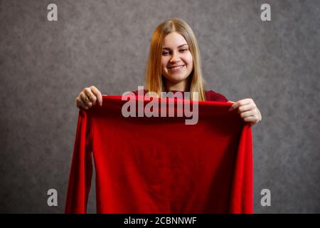 Schönes Mädchen versucht auf einem roten Pullover Stockfoto