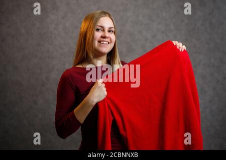 Schönes Mädchen versucht auf einem roten Pullover Stockfoto