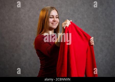 Schönes Mädchen versucht auf einem roten Pullover Stockfoto