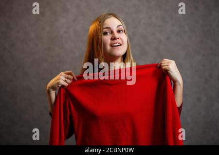 Schönes Mädchen versucht auf einem roten Pullover Stockfoto