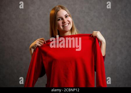 Schönes Mädchen versucht auf einem roten Pullover Stockfoto