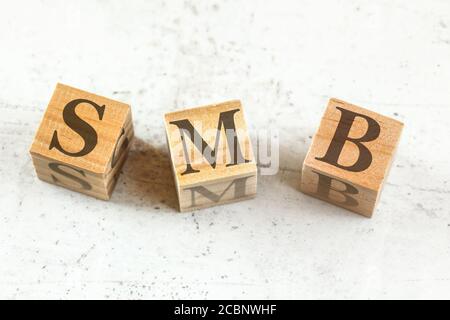 Drei Holzwürfel mit den Buchstaben SMB (steht für Small bis Medium Business) auf Whiteboard. Stockfoto