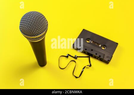 Mikrofon und Audiokassette mit etwas Magnetband heraus, auf gelber Platine. Stockfoto