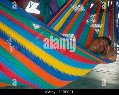 Amazon River, Peru - 08. Dez 2019: Porträt des Mannes, der auf der bunten Hängematte auf dem Frachtschiff schläft. Weg von Santa Rosa nach Iquitos. Amazonien. Sou Stockfoto