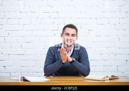 Ein junger Geschäftsmann Kerl sitzt an einem Tisch mit einem Buchen Stockfoto