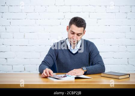 Ein junger Geschäftsmann Kerl sitzt an einem Tisch mit einem Buchen Stockfoto