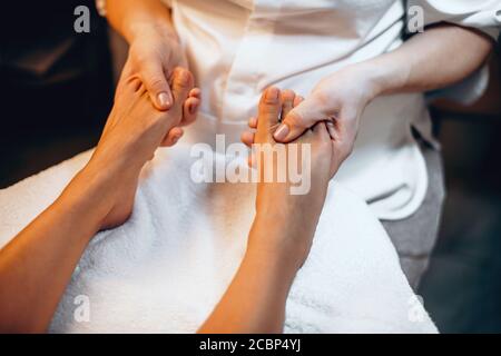 Kaukasische Dame sitzt auf einer Spa-Couch und mit Fuß Massage in einem modernen gesunden Zentrum Stockfoto